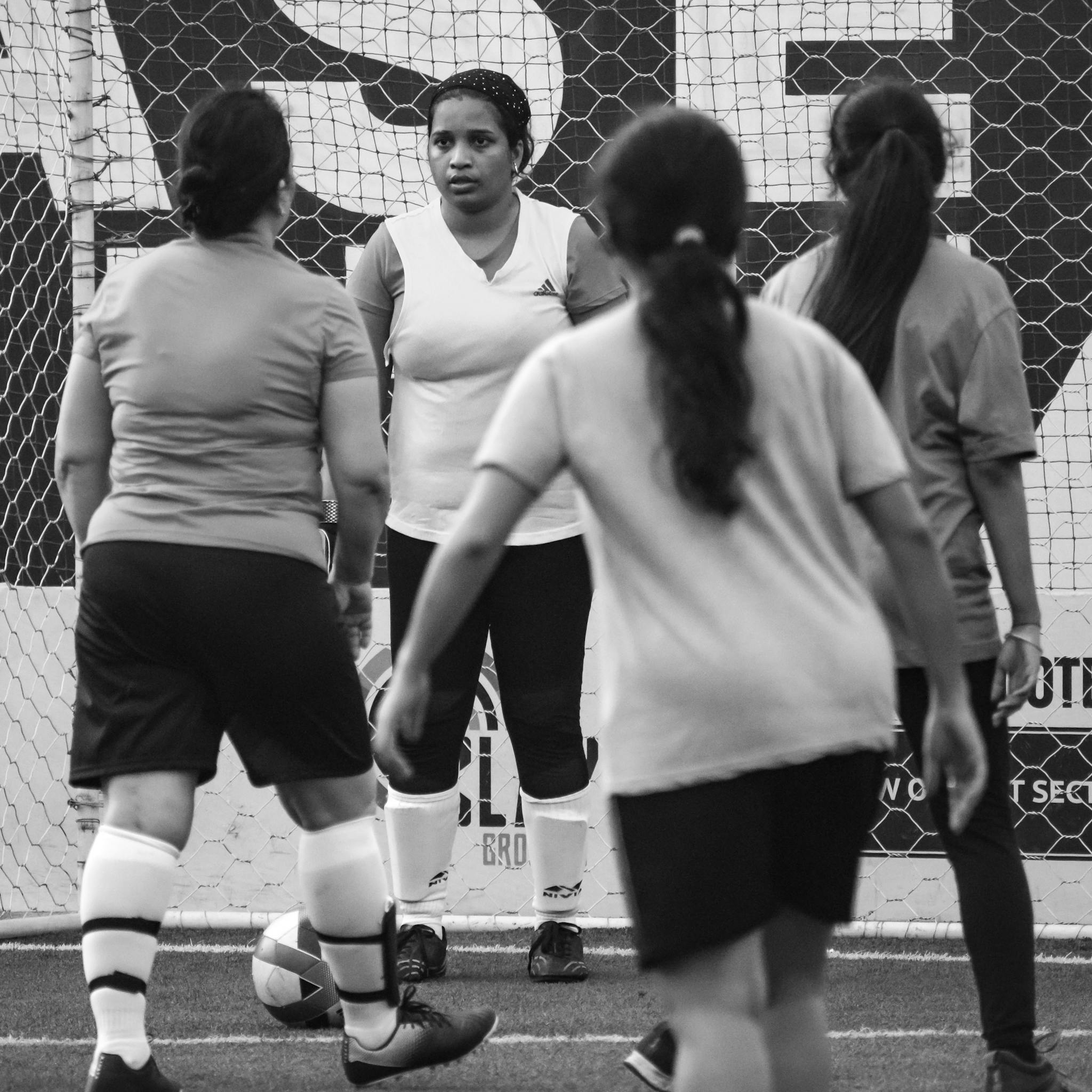 A group of women playing indoor soccer, conveying teamwork and sport spirit.